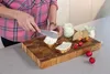 A person is spreading a creamy spread onto slices of bread on a wooden cutting board, with jars of spread and radishes nearby. Produktbild-Vorschau