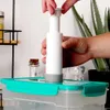 A person is using a white vacuum pump to seal a clear food container with a turquoise lid. Produktbild-Vorschau