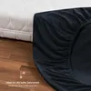 A dark blue fitted sheet is shown partially covering a white mattress, with a wooden floor in the foreground. Voir les images du produit