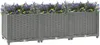 A long, gray, woven-textured planter box filled with purple and yellow flowers, set against a white background. Produktbild-Vorschau