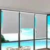 Roller blinds are installed on a large window overlooking a beach scene with boats and a green island. Produktbild-Vorschau
