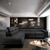 A modern living room with a dark sectional sofa and a stone accent wall. Produktbild-Vorschau