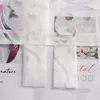 Close-up of a white sheer curtain with a floral pattern and text overlay. Produktbild-Vorschau