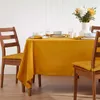 A dining table set with a yellow tablecloth, plates, glasses, and a vase of flowers. Anteprima dell’immagine prodotto