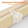 Close-up of a clear plastic clip attached to a beige window frame, holding a rolled-up beige fabric blind. Voir les images du produit