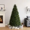 A decorated Christmas tree with presents underneath, next to a fireplace and a sofa. Produktbild-Vorschau