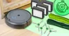 A collection of robot vacuum cleaner replacement parts, including filters, side brushes, and main brushes, laid out on a light green surface next to a robot vacuum cleaner. Voir les images du produit