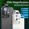 Two cell phone microscope attachments, one black and one white, are shown clipped onto smartphones against a green leafy background. Text overlays highlight product features. Produktbild-Vorschau