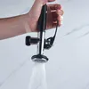 A hand holding a kitchen spray faucet with water spraying from it. Produktbild-Vorschau