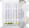 A white sheer curtain with lace trim hanging in a window. Produktbild-Vorschau