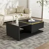 A modern black coffee table with a glass top and gold accents is placed on a patterned rug in a living room with a sofa in the background. Produktbild-Vorschau