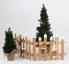 A wooden fence with small birdhouses and two small Christmas trees against a white background. Náhled obrázku produktu