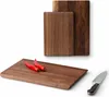Three wooden cutting boards of different sizes are arranged on a white background. Two red chili peppers are placed on the largest cutting board in the foreground, and a knife is placed to the right of it. Two smaller cutting boards are stacked behind the  Náhled obrázku produktu