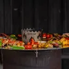 A close-up shot of a grill with various grilled foods and a metal wok attachment. Produktbild-Vorschau