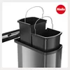 A close-up view of a dual-compartment trash bin insert with handles, placed inside a larger gray trash bin. The Hailo logo is visible in the upper right corner. Voir les images du produit