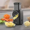 A black electric slicer is shown on a countertop, with various chopped vegetables and grains around it. Produktbild-Vorschau