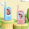 Two cartoon-style walkie-talkies, one blue and one pink, are displayed on colorful stands against a light yellow background with cartoonish green trees and clouds. Produktbild-Vorschau