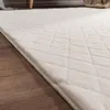 A close-up view of a white, plush rug with a diamond pattern, lying on a wooden floor. Anteprima dell’immagine prodotto