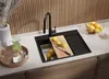 A modern kitchen sink area with a black granite sink, a wooden cutting board with lemons, a pitcher of green liquid, and a bowl of oranges. Produktbild-Vorschau