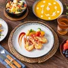 A table setting with a meal, including soup, fruit salad, and a main course of shrimp with vegetables. Produktbild-Vorschau