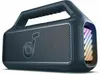 A dark gray portable speaker with a handle and a silver grille on the front. The right side of the speaker has colorful LED lights. Voir les images du produit