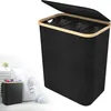 A black laundry basket with a beige rim and lid, shown open to reveal three compartments. A smaller inset image shows the basket filled with clothes next to a washing machine. Voir les images du produit