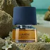 A bottle of perfume is placed on a beach with rocks and flowers. Podgląd zdjęcia produktu