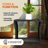 A black polyrattan side table with a potted plant on top, placed near a window with a garden view. Anteprima dell’immagine prodotto
