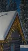 A snow-covered cabin with Christmas lights strung across the roof. Náhľad obrázku produktu
