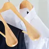 A close-up shot of two wooden hangers holding clothing, with a white shirt and black pants visible. Produktbild-Vorschau