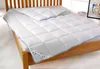 A white quilted duvet is laid out on a wooden bed frame. Produktbild-Vorschau