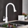 A white kitchen faucet is shown in a kitchen sink with some fruit in a drying rack. Náhľad obrázku produktu