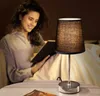 A woman is reading a book in bed, illuminated by a bedside lamp. Produktbild-Vorschau