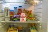The image shows the inside of a refrigerator with various food and drink items on the shelves. Podgląd zdjęcia produktu