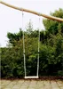 A wooden swing hanging from a tree branch in a garden setting. Podgląd zdjęcia produktu