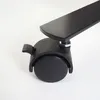 A close-up view of a black caster wheel with a locking mechanism attached to a black metal bar. Produktbild-Vorschau