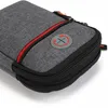 Close-up of a gray fabric pouch with red and black zipper details and a circular gray logo with a red 'X' symbol. Produktbild-Vorschau