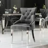 A grey velvet dining chair with silver legs and studding, placed in a dining room setting. Produktbild-Vorschau