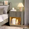 A bedside table with items on and in it, next to a bed. Anteprima dell’immagine prodotto