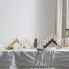 A table set with a white tablecloth, decorated with multiple candle holders and lit candles, creating a festive atmosphere. Podgląd zdjęcia produktu