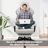 A man is sitting cross-legged in a gaming chair with a laptop on his lap, in a well-lit room with a plant and a floor lamp. Náhled obrázku produktu