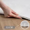 A hand is shown pressing down on the edge of a white rug, demonstrating its thickness. A close-up inset shows a measurement of 1.1 cm. Náhled obrázku produktu
