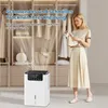 A woman is holding clothes in front of a dehumidifier in a closet. Anteprima dell’immagine prodotto