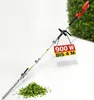 A long-reach hedge trimmer is shown diagonally against a white and green background, with a pile of cut leaves at its base. Produktbild-Vorschau