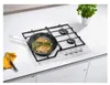A white gas hob with a frying pan on it, cooking food. A whisk and a yellow napkin are on the left. A potted plant is on the right. Anteprima dell’immagine prodotto
