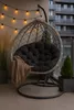A hanging egg chair with a black cushion and a brown throw blanket is set up on a balcony, decorated with string lights. Anteprima dell’immagine prodotto