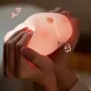 Hands holding a glowing pink pig-shaped night light. Podgląd zdjęcia produktu
