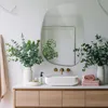 A modern bathroom vanity with a sink, mirror, and decorative elements. Produktbild-Vorschau