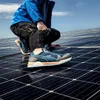 A person kneeling on solar panels, adjusting their shoe. Náhľad obrázku produktu