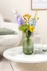 A bouquet of flowers in a green vase on a marble coffee table next to a fluffy white armchair. Náhled obrázku produktu